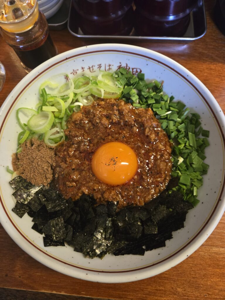 Close-up of Maze-Soba toppings including chives, green onions, and a raw egg yolk.