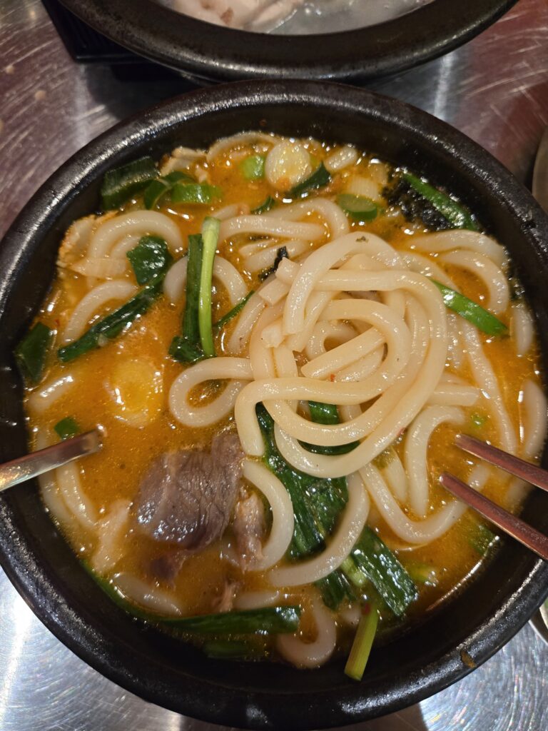 Eolkeun Pork Udon with spicy broth and tender pork slices at Subyeon Saego Pork Rice Soup Seomyeon.
